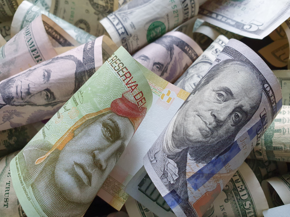 Billetes de dólares estadounidenses y soles peruanos enrollados, representando conceptos de contabilidad, inversión y tipo de cambio monetario.